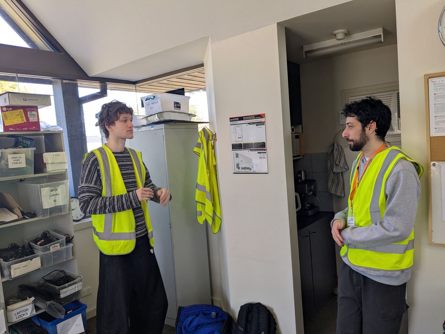 Two front desk volunteers in hi-vis vests chatting in the showroom